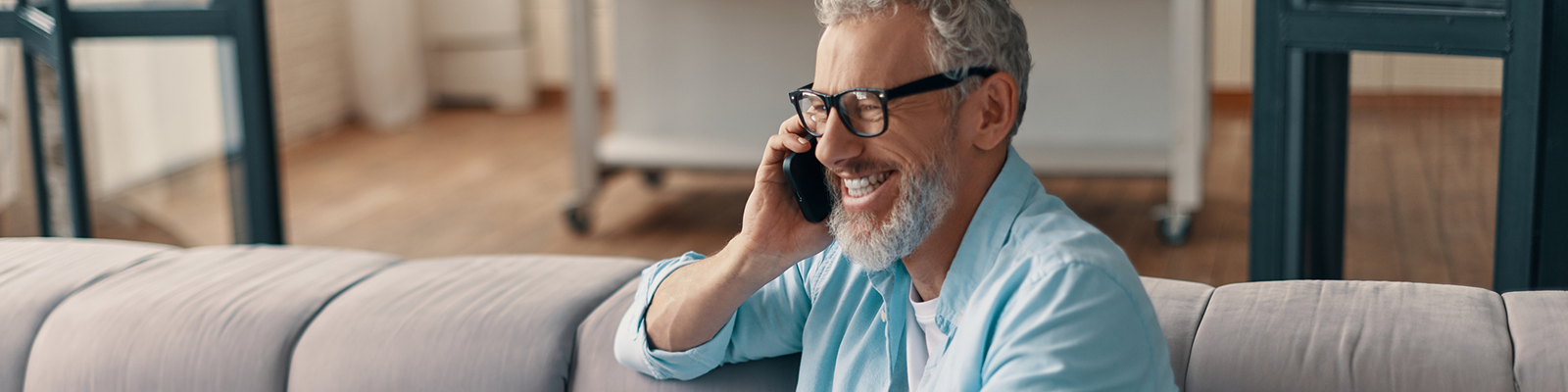 man sitting on his sofa, talking on a phone