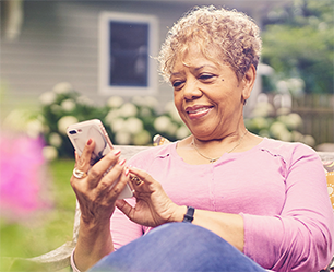 A woman sitting in her garden looking at her smart phone